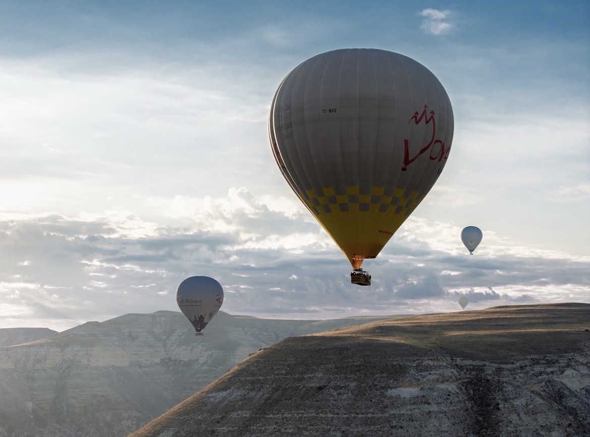 Hot air balloons rising over Cappadocia at sunrise, seen by our line producer in Cappadocia