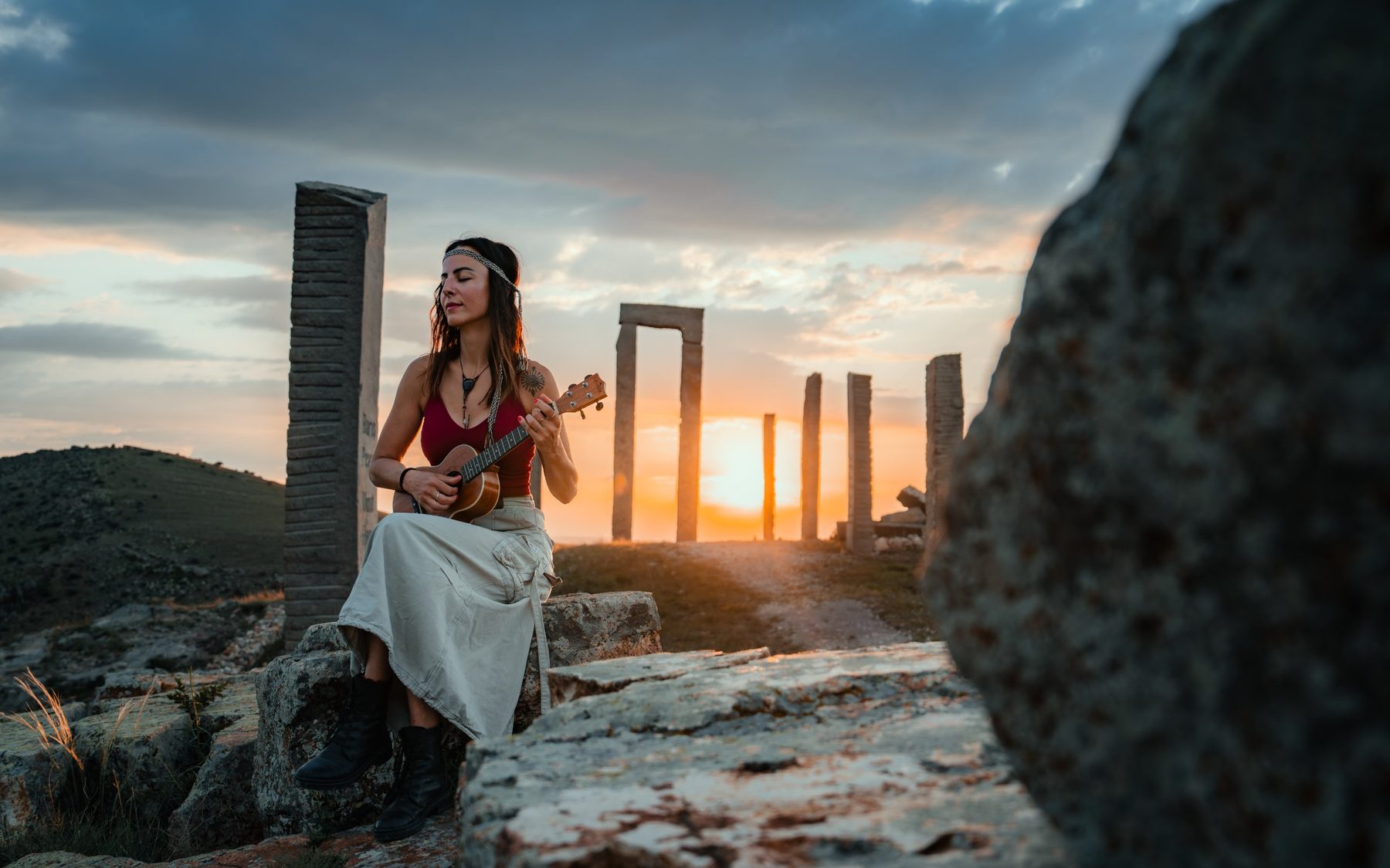 Musician playing the ukulele among stone columns at sunset in Cappadocia