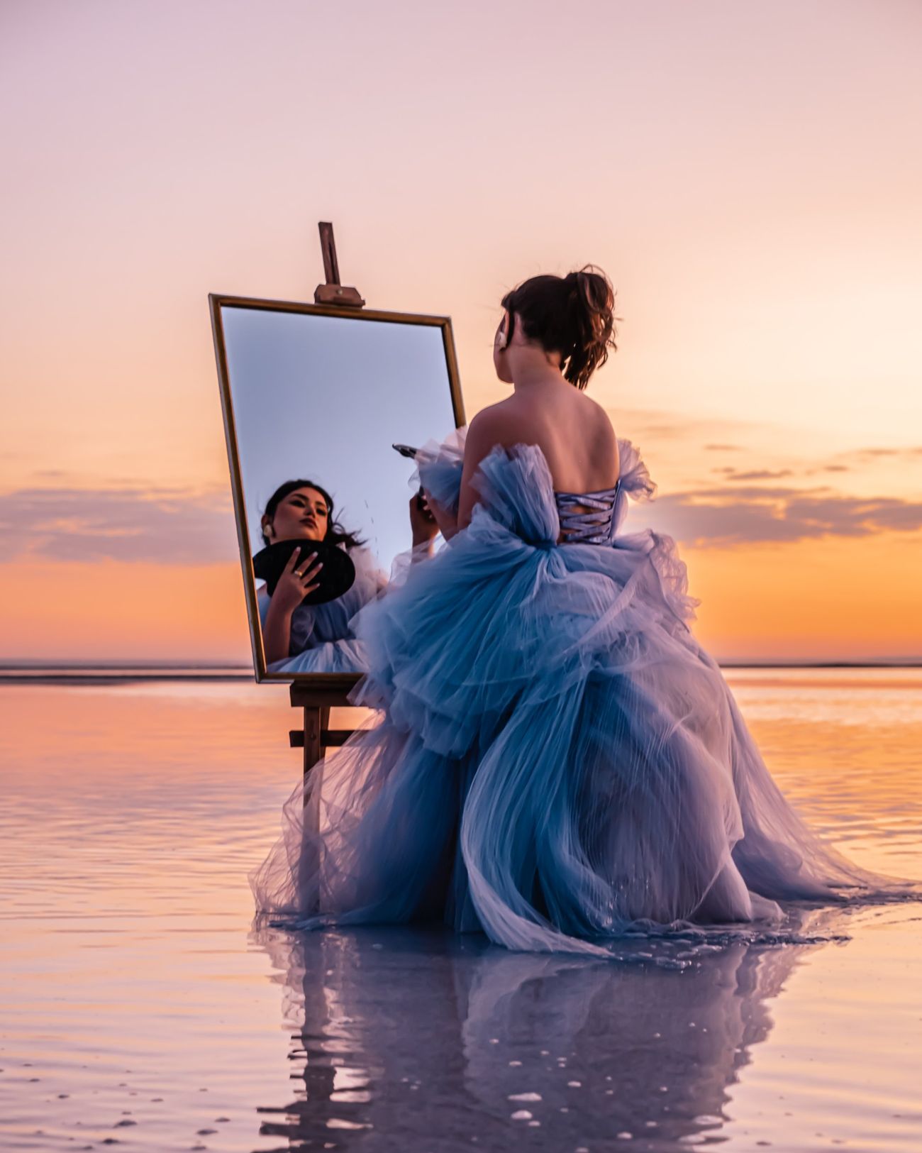 Cappadocia photographer, woman in a blue gown painting her reflection in a mirror on Salt Lake at sunset