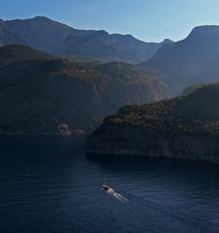 A sailing boat below mountains on the Turkish turquoise coast